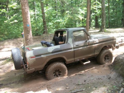 1979 Ford Bronco - This 1978 Ford Bronco navigates a challenging muddy terrain in a wooded area.