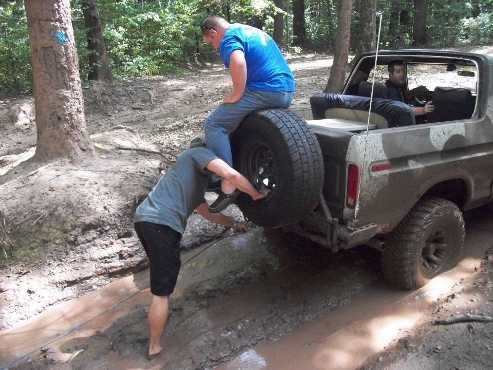 1979 Ford Bronco stuck in mud, rear view, camouflage paint