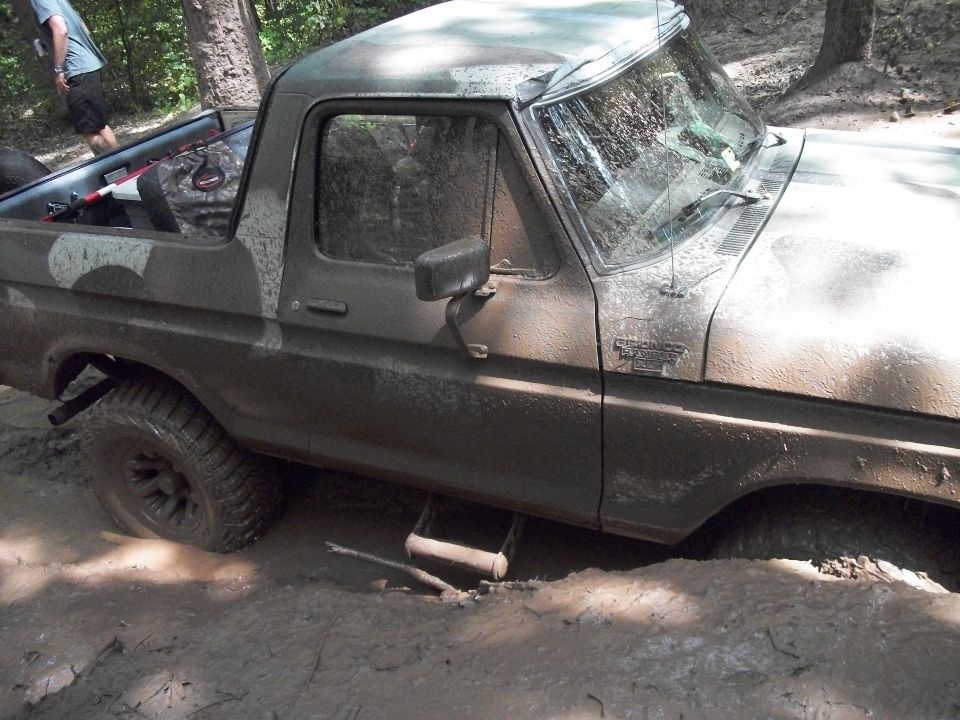 Mud-covered 1979 Ford Bronco stuck in mud, off-road tires visible