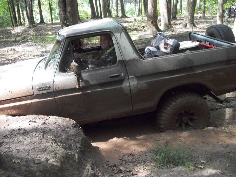1979 Ford Bronco - This muddy Ford Bronco is stuck in a ditch, with a driver smiling from behind the wheel.