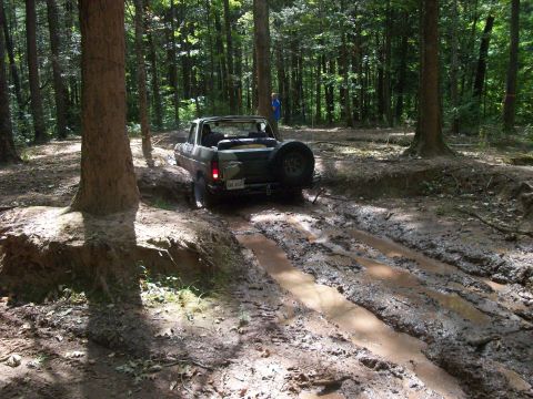 1979 Ford Bronco - A 1978 Ford Bronco navigates a challenging muddy track in a wooded area.