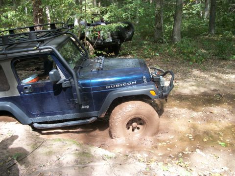 1979 Ford Bronco - Two Jeeps are stuck in the mud during an off-road excursion in a wooded area.