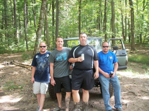 1979 Ford Bronco - Four men pose with a 1979 Ford Bronco in a wooded area, its door open.