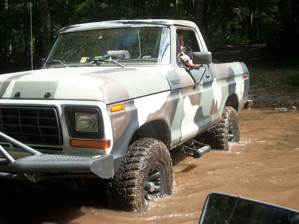 Ford F-Series pickup truck with camouflage paint driving through water