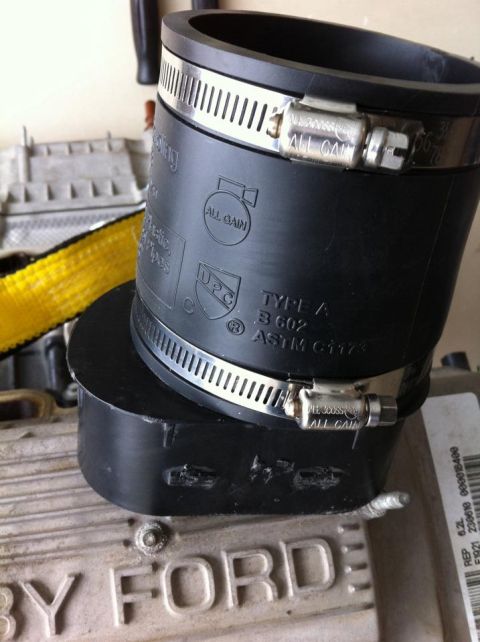 2010 Ford F-150 - A black rubber hose with metal clamps is shown on top of a Ford component, with visible text and part numbers.
