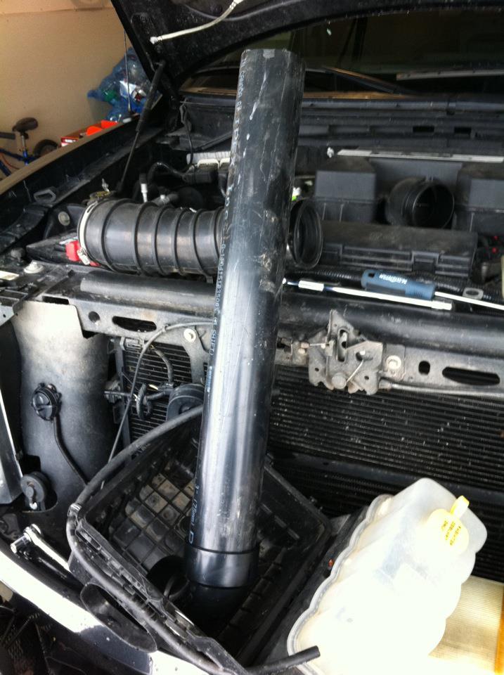 2010 Ford F-150 engine bay with air intake removed and a large pipe inserted