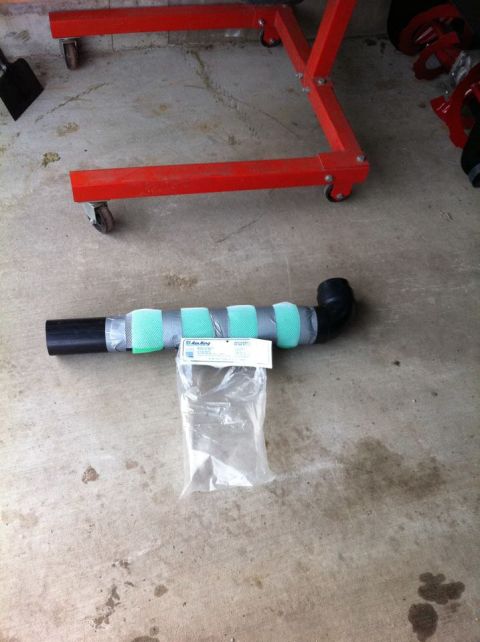 2010 Ford F-150 - An exhaust pipe section with padding and a bag of parts rests on a concrete garage floor.