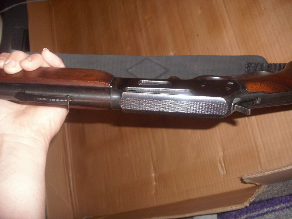 Close-up of a firearm receiver with wood stock, held by a hand