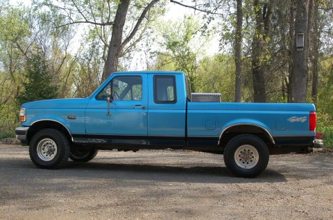 1992 Ford F-150 - Side view of a blue 1992 Ford F-150 extended cab pickup truck with a toolbox in the bed.