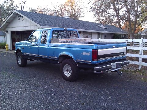 1992 Ford F-150 - A blue 1992 Ford F-150 pickup truck is parked in front of a house and garage.