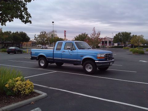 1992 Ford F-150 - This blue 1992 Ford F-150 crew cab pickup truck is seen from a three-quarter front view in a parking lot.