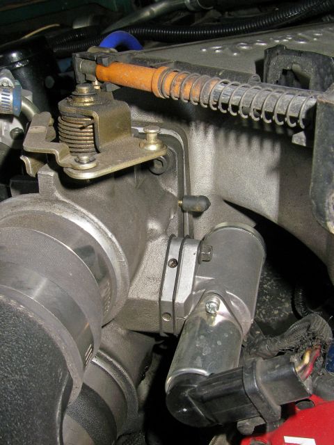1990 Ford Bronco - This image shows a throttle body and its associated sensor and linkage mechanism.