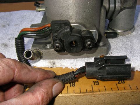 1990 Ford Bronco - Aluminum throttle body or EGR housing held over a ruler, with detached two-wire connector and pigtail.