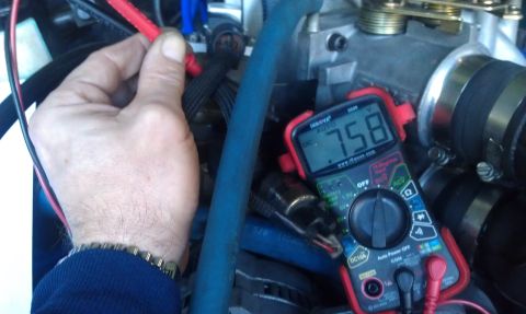 1990 Ford Bronco - A multimeter displays a voltage reading while being used to test engine components.