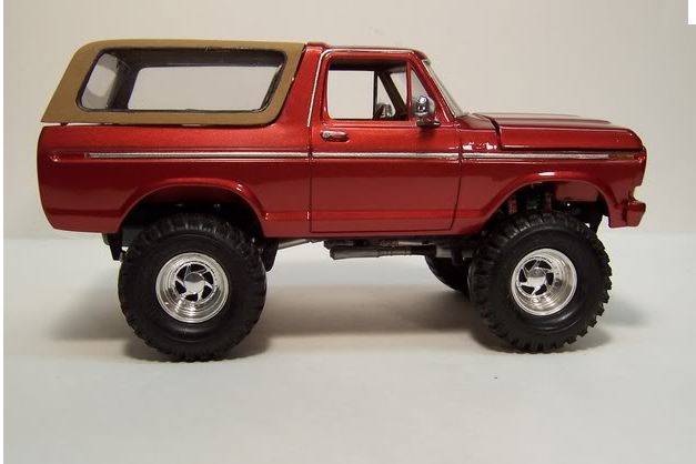 Side view of red Ford Bronco scale model with tan top and lifted off-road tires