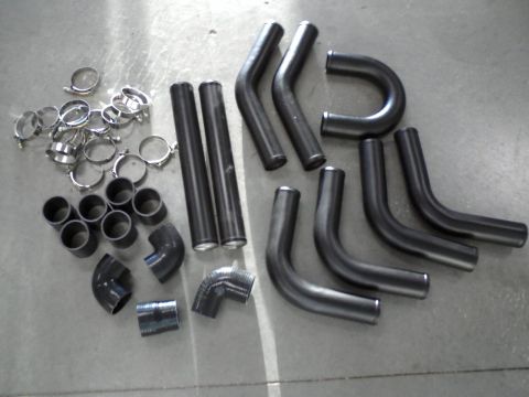 1987 Ford Bronco - Various exhaust pipe bends and assorted clamps are laid out on a gray surface.
