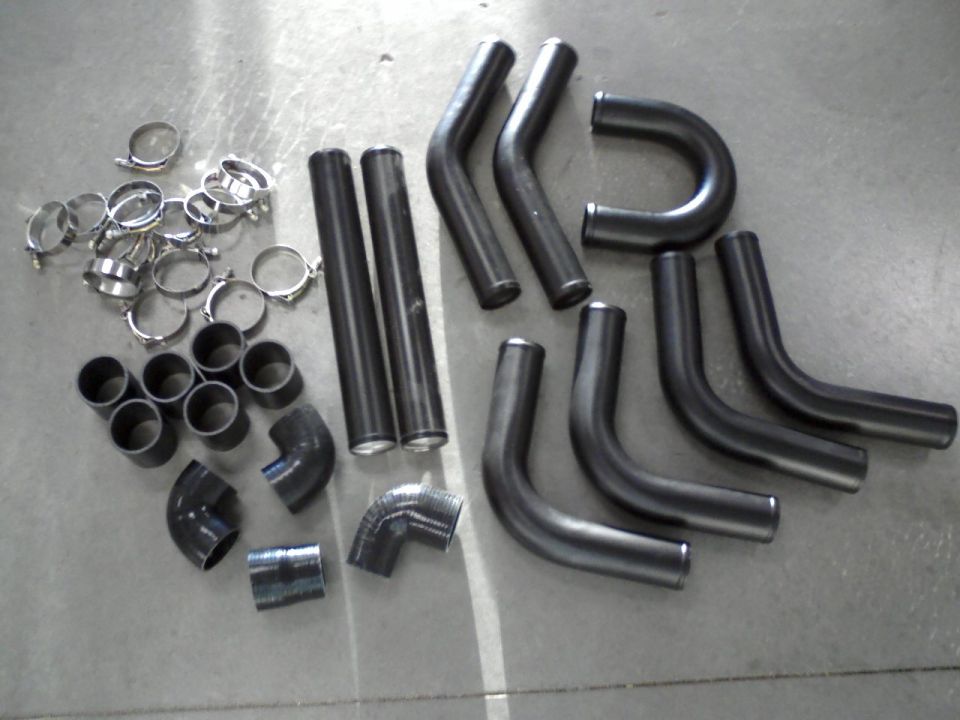 Collection of bent metal pipes and hose clamps on a concrete surface