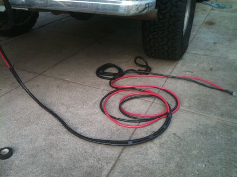 1996 Ford Bronco - Red and black winch wiring is laid out on concrete near the undercarriage of a vehicle.