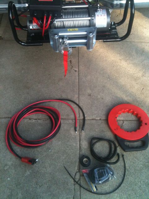 1996 Ford Bronco - A winch and wiring kit is laid out on a concrete surface, including coiled cables and electrical tape.