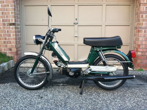 1981 Garelli Rally Sport - A green moped with a black seat and exhaust is parked in front of a beige garage door.