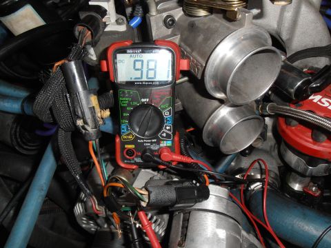 1990 Ford Bronco - A multimeter reads 0.98 volts while connected to engine components, likely for diagnostics.