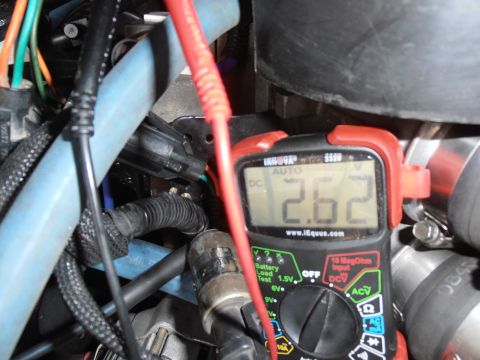1990 Ford Bronco - A digital multimeter is used to measure voltage within a vehicle's engine bay, showing a reading of 2.62 volts.