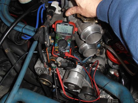 1990 Ford Bronco - Digital multimeter showing 46 used to test an engine; blue spark plug wires, alternator and throttle body visible.