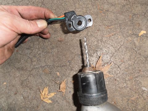1990 Ford Bronco - A throttle position sensor and a drill bit are shown on a concrete surface with dry leaves.
