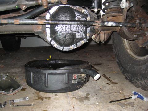 2005 Jeep Wrangler - A black differential cover with a silver "SOLID" logo is shown, with a drain pan underneath to catch fluid.