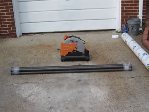1994 Ford Bronco - Metal cutting saw and pipes are laid out on a concrete driveway in front of a garage door.