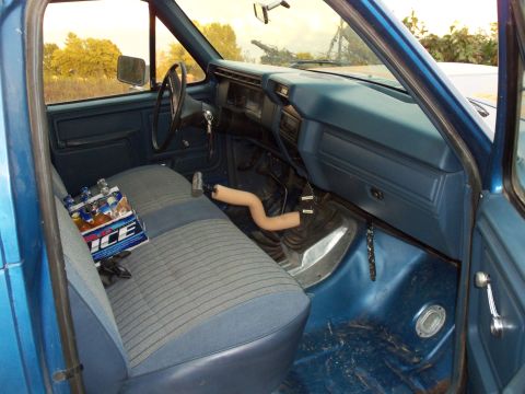 1985 Ford Bronco - The interior of a blue truck, likely from the early 1980s, shows its dashboard, seats, and floor shifter.