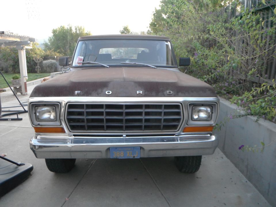 Brown 1979 Ford Bronco front view, rusty hood, chrome grille, blue license plate
