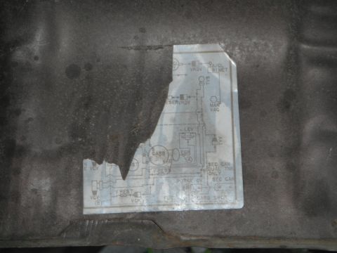 1979 Ford Bronco - A torn sticker with an engine vacuum diagram is affixed to a dark surface.