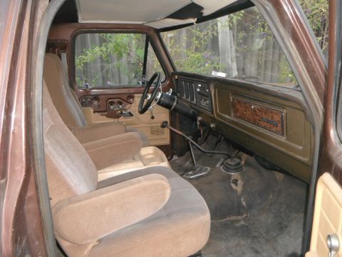 1979 Ford Bronco - The interior of a 1979 Ford Bronco features dual front bucket seats and a wood-grain accented dashboard.