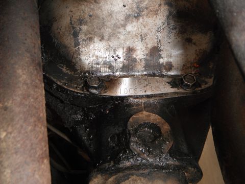 1979 Ford Bronco - A metal tag with identification numbers is attached to the greasy differential housing of a vehicle.