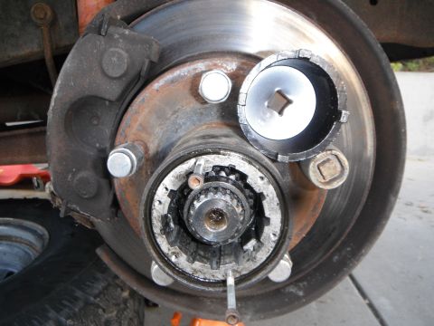1979 Ford Bronco - Close-up of a vehicle's front hub assembly, showing the brake rotor, caliper, and a specialized tool.