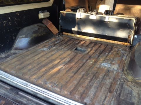 1979 Ford Bronco - The cargo area of the vehicle shows significant rust on the floor panels and a metal seat frame.