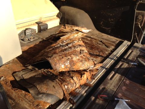 1979 Ford Bronco - The interior floor pan of a vehicle shows significant rust and damage.