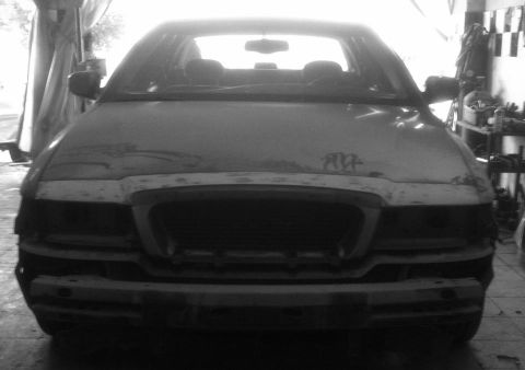 2001 Mercury Grand Marquis - The front of a 2001 Mercury Grand Marquis is shown, with the grille and bumper removed, inside a workshop.
