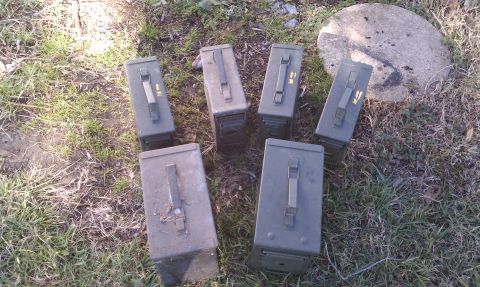 1979 Ford Bronco - A collection of military surplus ammo cans rests on the grass next to a large rock.