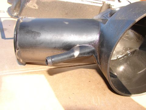 1973 Ford Ranchero - A close-up view of a black plastic automotive component with a small hose nipple attached.
