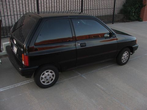1991 Ford Festiva - A black 1991 Ford Festiva is parked outdoors, showing its side and front-right profile.