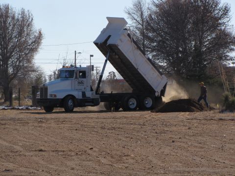 1995 Ford Bronco - A dump truck unloads dirt at a construction site.
