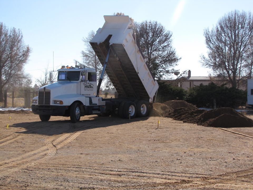 White dump truck unloading dirt, side view