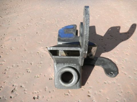1997 Ford Ranger - A metal trailer hitch part sits on a sandy surface, casting a shadow.