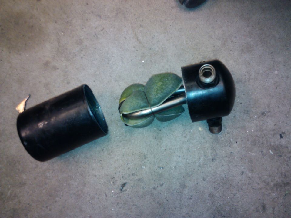 Disassembled black automotive part with green fins inside a metal casing