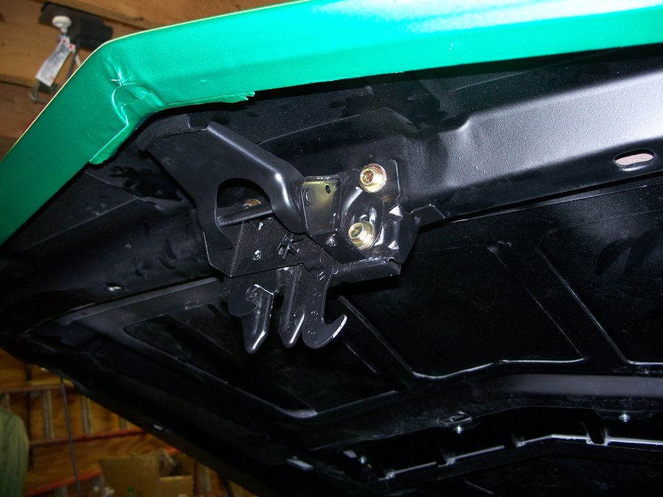 Underside of green hood showing latch mechanism and mounting hardware