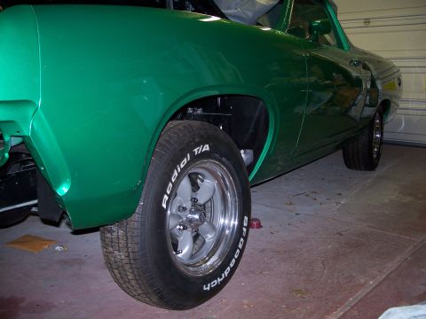 1971 Ford Ranchero - A green car is viewed from the side, revealing its front wheel and fender.