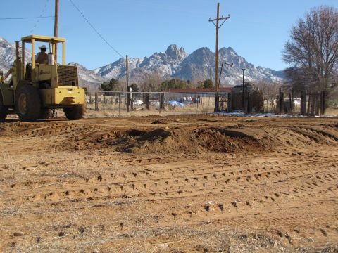 1995 Ford Bronco - A yellow front loader is seen operating on a dirt construction site with mountains in the distance.