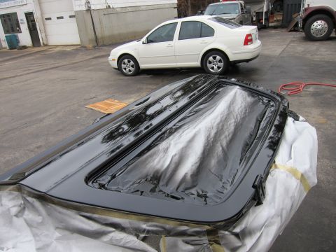 1987 Dodge 1500 - A freshly painted car sunroof panel is covered for protection, with other vehicles visible in the background.